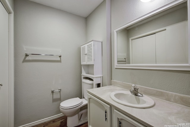 bathroom featuring hardwood / wood-style flooring, toilet, and vanity with extensive cabinet space