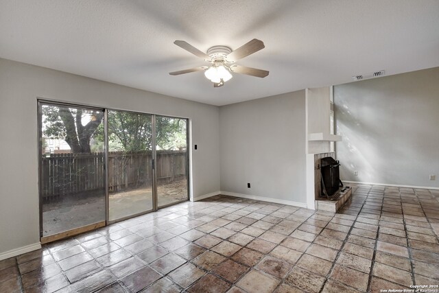 unfurnished living room with a brick fireplace, ceiling fan, and tile floors