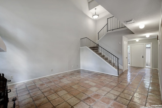 entrance foyer with visible vents, a high ceiling, stairs, and baseboards