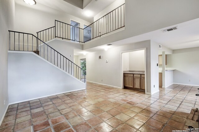 unfurnished living room with a towering ceiling and light tile floors