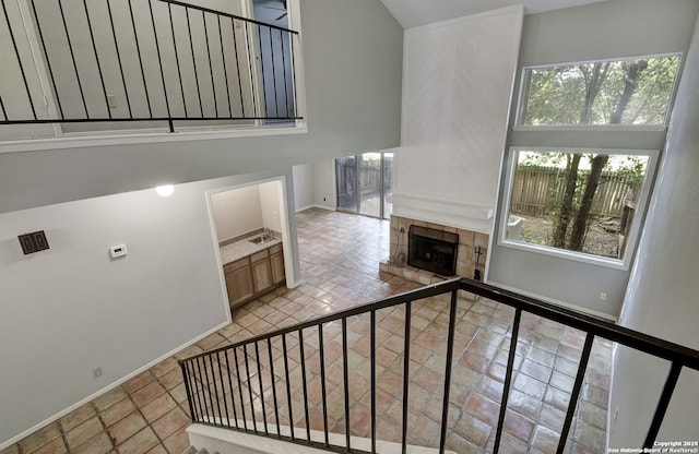 staircase featuring a tiled fireplace, baseboards, and a towering ceiling