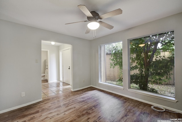 empty room with baseboards, wood finished floors, and a ceiling fan