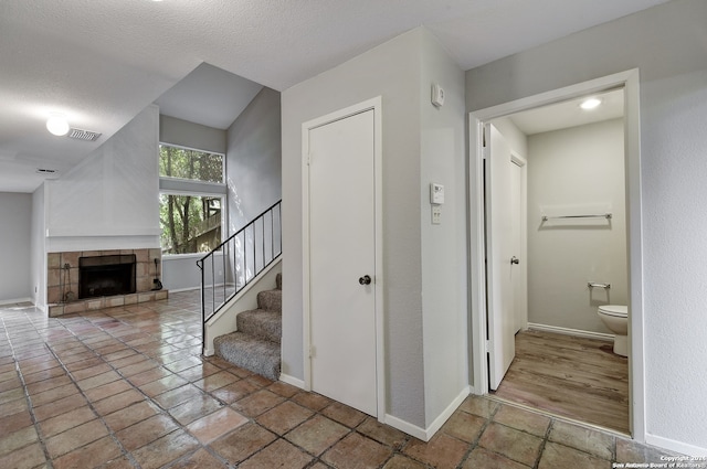 stairway featuring a textured ceiling, a fireplace, visible vents, and baseboards