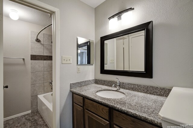 bathroom featuring tile floors, tiled shower / bath, and vanity