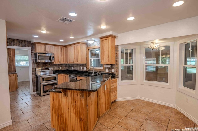 kitchen featuring tasteful backsplash, sink, stainless steel appliances, and dark stone counters