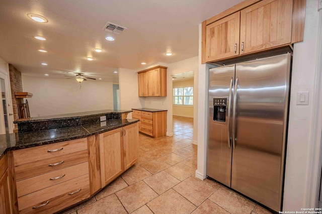 kitchen featuring light brown cabinetry, stainless steel fridge, dark stone counters, and ceiling fan