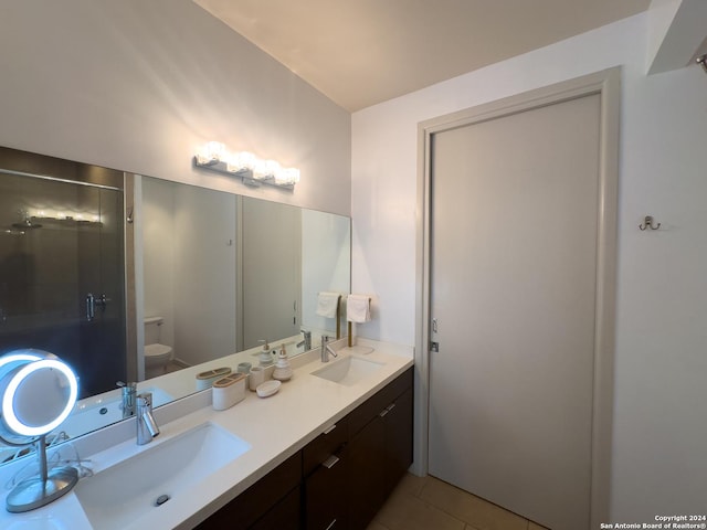 bathroom with tile patterned flooring, vanity, toilet, and walk in shower