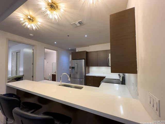 kitchen featuring sink, a kitchen bar, kitchen peninsula, stainless steel appliances, and a chandelier