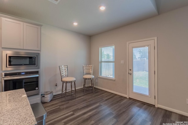 kitchen featuring appliances with stainless steel finishes, dark hardwood / wood-style floors, light stone counters, and white cabinetry