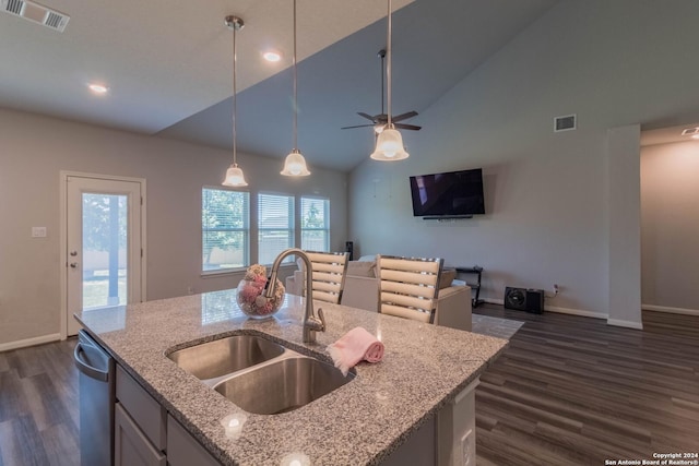 kitchen with sink, light stone counters, dark hardwood / wood-style floors, pendant lighting, and a kitchen island with sink