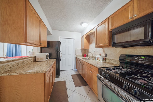 kitchen featuring sink, tasteful backsplash, a textured ceiling, light tile patterned floors, and black appliances