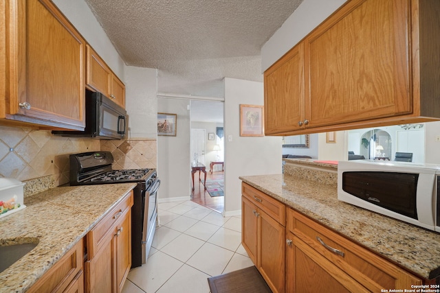 kitchen featuring decorative backsplash, light tile patterned floors, a textured ceiling, and black appliances