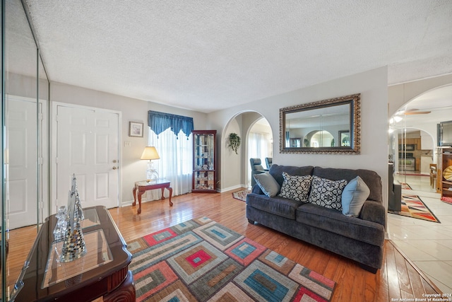 living room with ceiling fan, wood-type flooring, and a textured ceiling