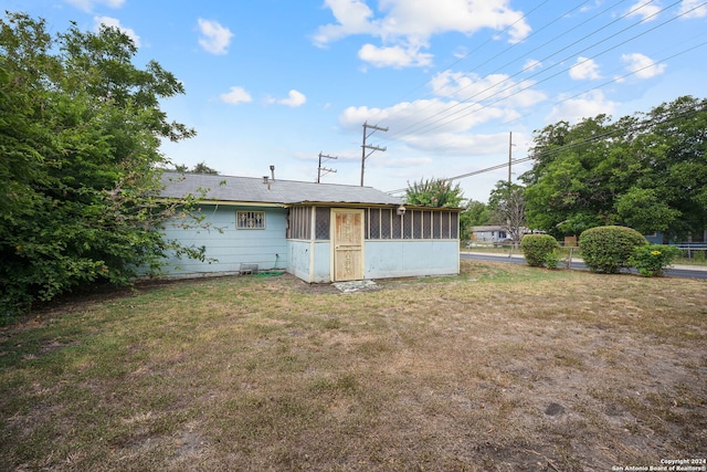 rear view of house with a lawn and a sunroom