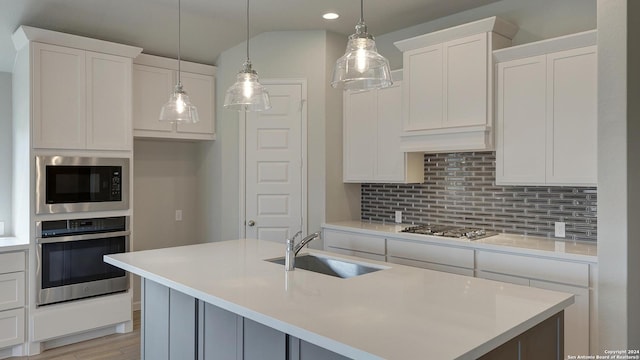 kitchen with white cabinets, sink, stainless steel appliances, and hanging light fixtures