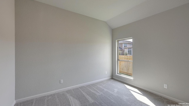 spare room featuring light colored carpet and lofted ceiling