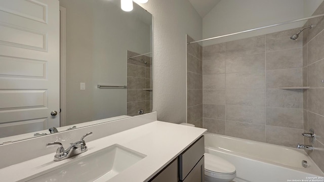 full bathroom featuring toilet, vanity, lofted ceiling, and tiled shower / bath