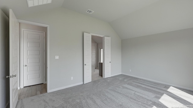 unfurnished bedroom with lofted ceiling and light carpet