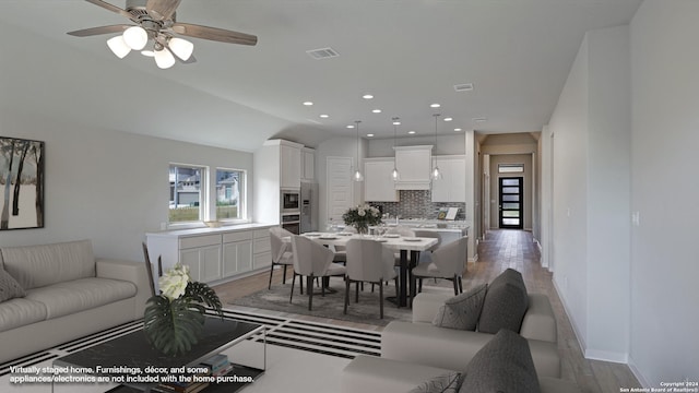 living room featuring vaulted ceiling, light hardwood / wood-style flooring, and ceiling fan