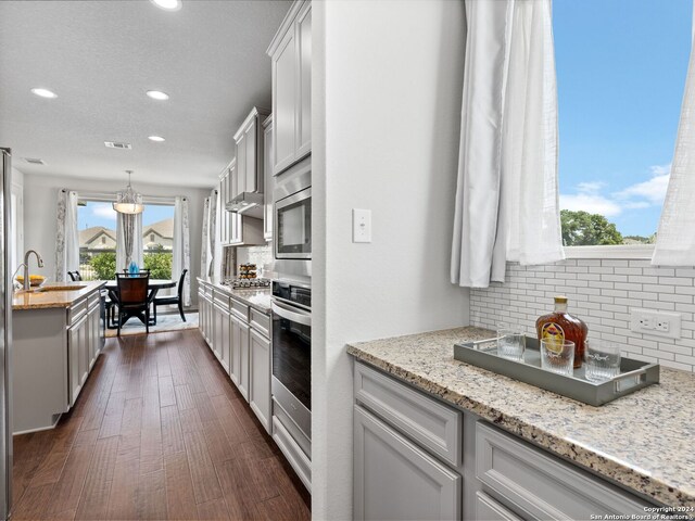 kitchen with light stone counters, dark hardwood / wood-style flooring, tasteful backsplash, white cabinetry, and pendant lighting