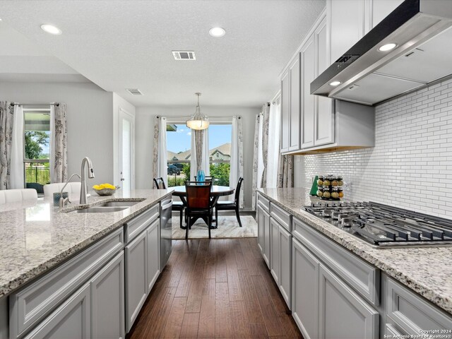 kitchen featuring wall chimney range hood, appliances with stainless steel finishes, dark hardwood / wood-style floors, a healthy amount of sunlight, and sink