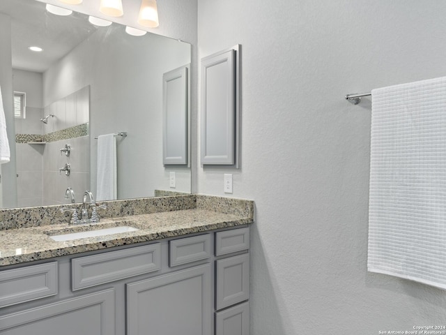 bathroom featuring a tile shower and large vanity