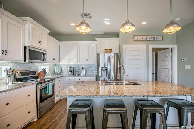 kitchen with appliances with stainless steel finishes, a kitchen island with sink, and white cabinets