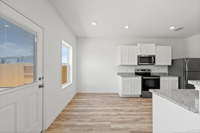 kitchen featuring stainless steel appliances, white cabinetry, light stone countertops, and light hardwood / wood-style floors