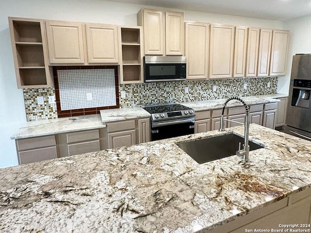 kitchen with stainless steel appliances, sink, backsplash, and light stone counters