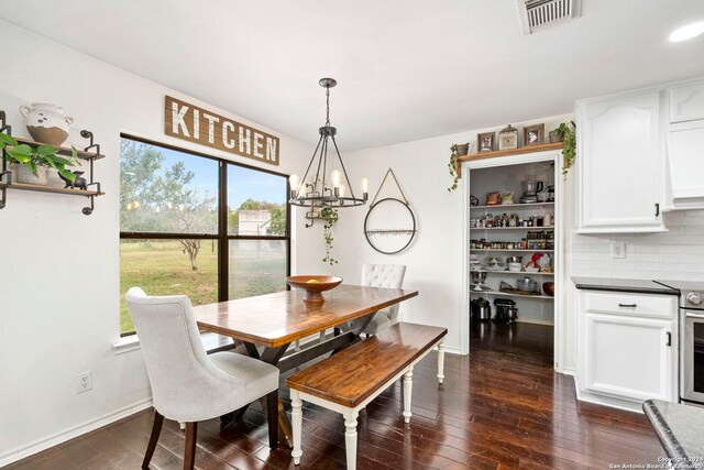 dining space with a notable chandelier, dark wood-type flooring, and sink