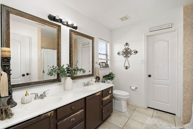 bathroom featuring tile flooring, oversized vanity, dual sinks, and toilet