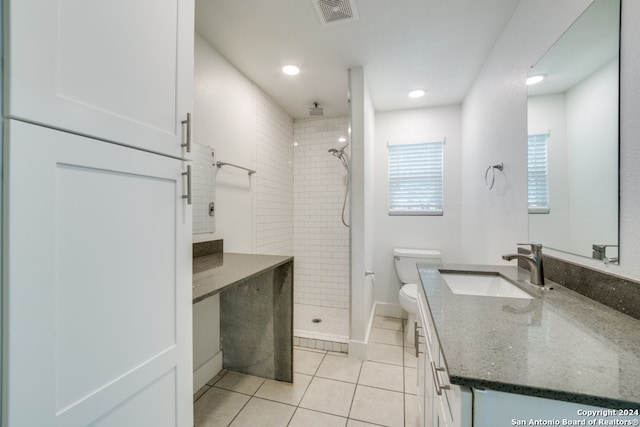 bathroom featuring a tile shower, oversized vanity, toilet, and tile floors