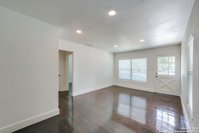 unfurnished room featuring dark hardwood / wood-style flooring and a textured ceiling