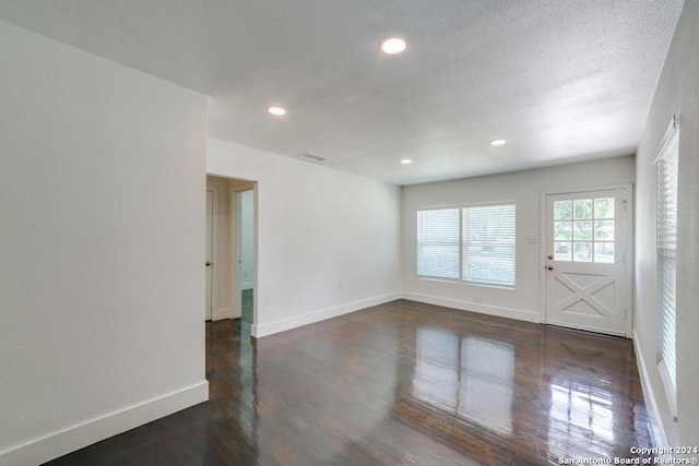 unfurnished room featuring dark hardwood / wood-style floors and a textured ceiling