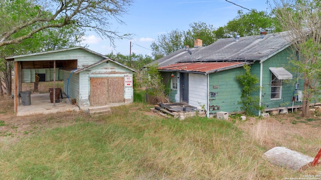 back of house featuring a carport, an outdoor structure, driveway, and a garage