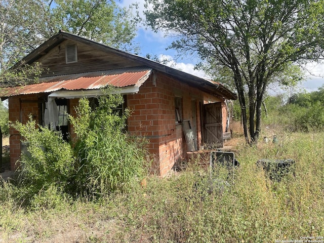 view of side of home with an outbuilding, metal roof, and brick siding