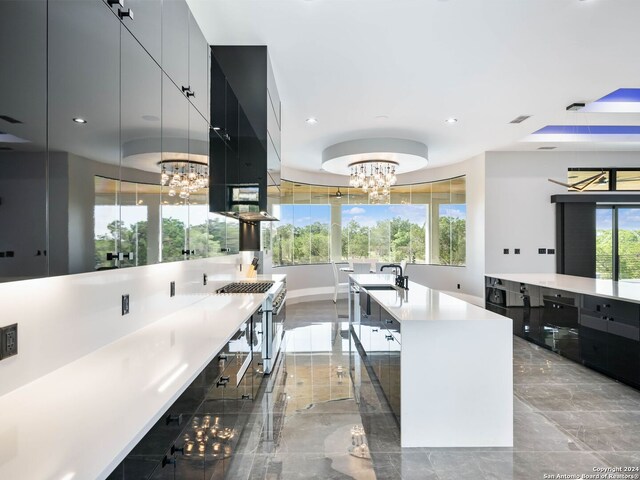 kitchen featuring light tile patterned flooring, high end stainless steel range, a chandelier, wall chimney range hood, and an island with sink