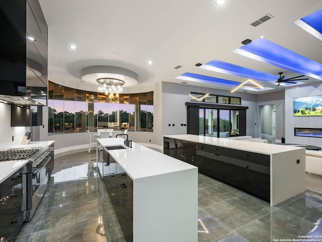 kitchen with tile patterned floors, ceiling fan with notable chandelier, high end stainless steel range, and a large island