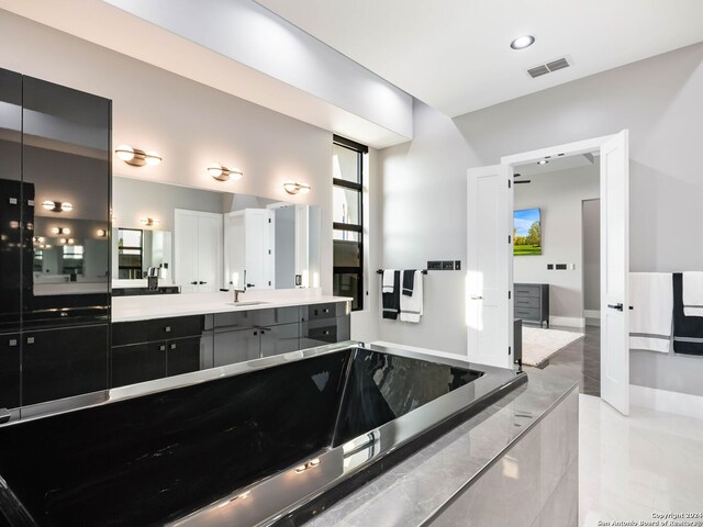 bathroom with tile patterned flooring, a washtub, and vanity