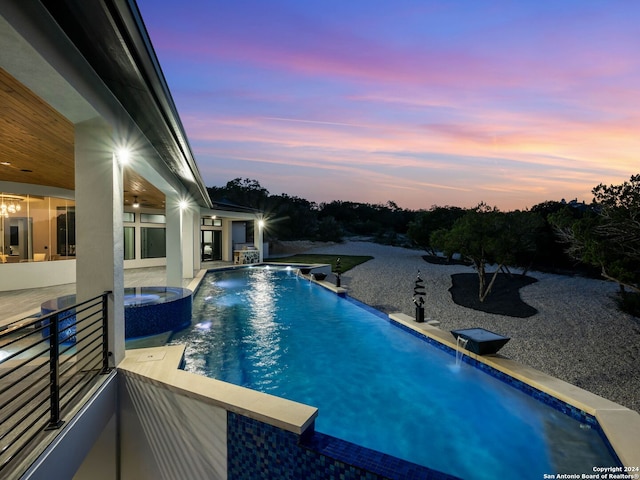 pool at dusk featuring a patio and pool water feature