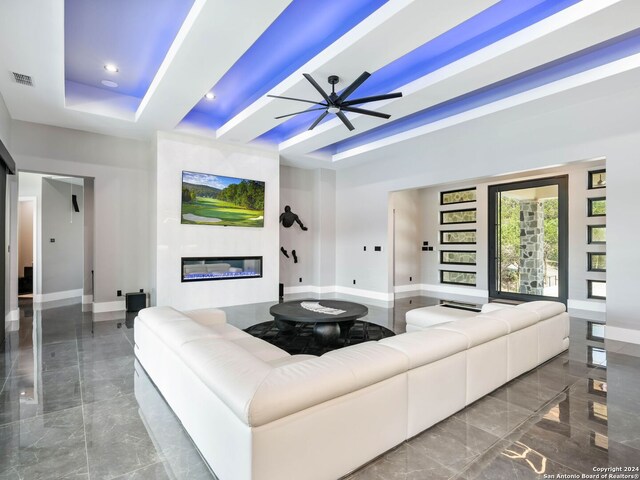 tiled living room featuring ceiling fan and a tray ceiling