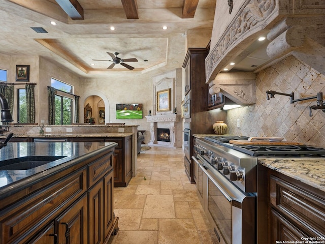 kitchen with light stone countertops, ceiling fan, stainless steel appliances, backsplash, and light tile floors