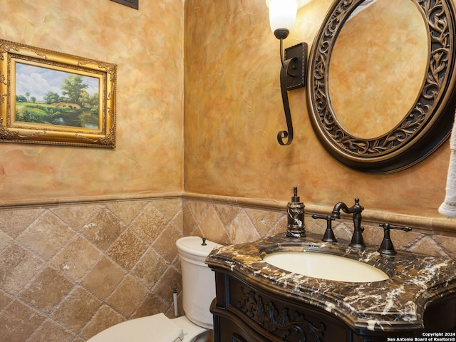 bathroom with backsplash, vanity, toilet, and tile walls