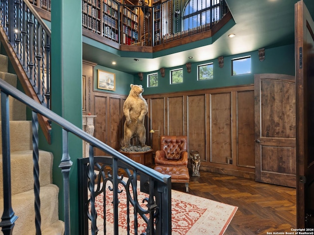 interior space with dark parquet flooring and a towering ceiling