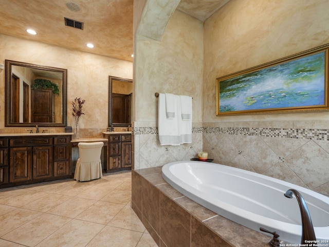 bathroom with tile floors, tiled tub, and vanity