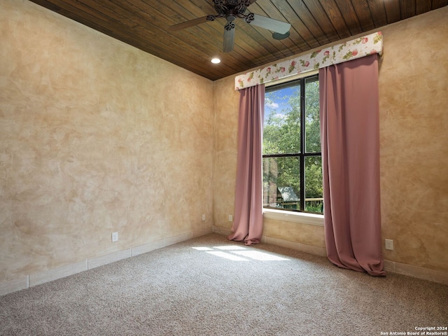 carpeted empty room featuring plenty of natural light, ceiling fan, and wooden ceiling