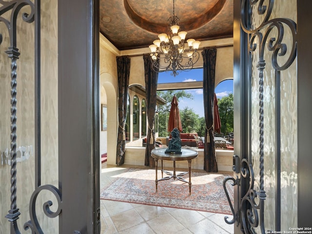 foyer entrance with tile floors, a raised ceiling, and a chandelier