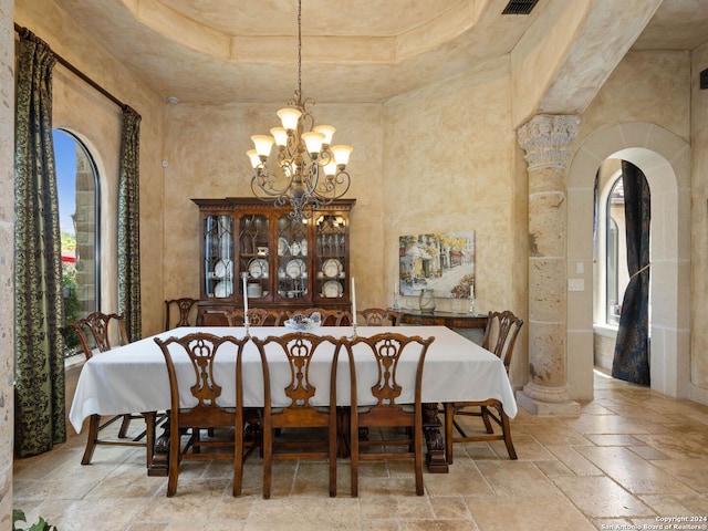 tiled dining room featuring a high ceiling, a tray ceiling, a wealth of natural light, and a chandelier