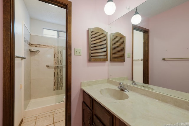 bathroom with a tile shower, vanity, and a textured ceiling