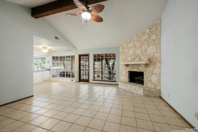 unfurnished living room with ceiling fan, a stone fireplace, beamed ceiling, a textured ceiling, and light tile patterned floors